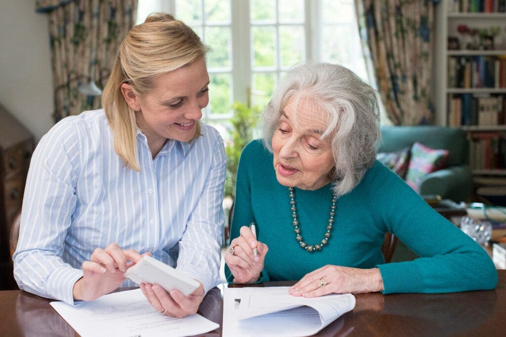Woman Helping Senior Neighbor With Paperwork Woman Helping Senior Neighbor With Paperwork
