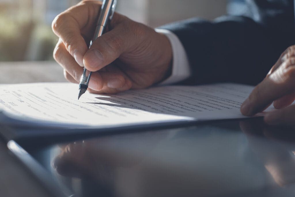 Signing contract Business man in black suit signing contract document with ldigital tablet on office desk, deal concept, close up